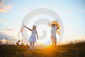 Happy children launch a kite in the field at sunset. Little boy and girl on summer vacation.