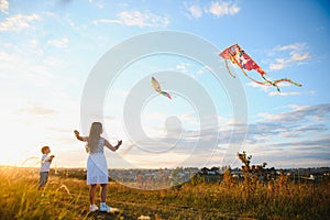 Happy children launch a kite in the field at sunset. Little boy and girl on summer vacation.