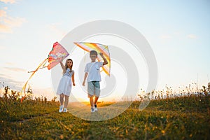 Happy children launch a kite in the field at sunset. Little boy and girl on summer vacation.