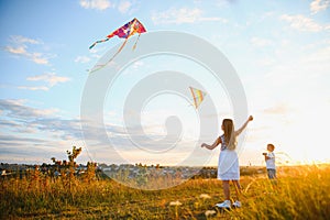 Happy children launch a kite in the field at sunset. Little boy and girl on summer vacation.