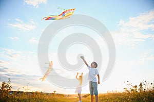 Happy children launch a kite in the field at sunset. Little boy and girl on summer vacation.