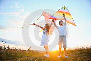 Happy children launch a kite in the field at sunset. Little boy and girl on summer vacation.