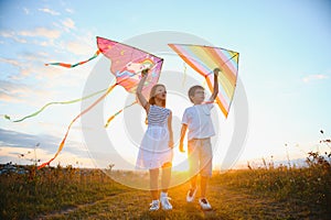 Happy children launch a kite in the field at sunset. Little boy and girl on summer vacation.