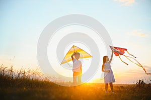 Happy children launch a kite in the field at sunset. Little boy and girl on summer vacation.