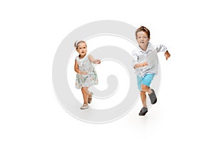 Happy children, little caucasian boy and girl jumping and running isolated on white background