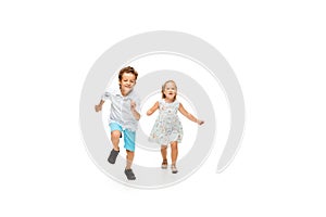 Happy children, little caucasian boy and girl jumping and running isolated on white background