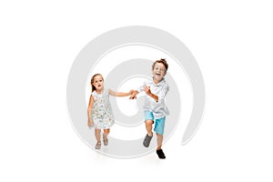 Happy children, little caucasian boy and girl jumping and running isolated on white background