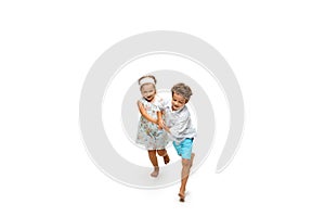 Happy children, little caucasian boy and girl jumping and running isolated on white background