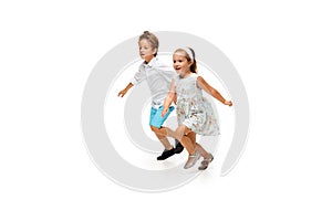 Happy children, little caucasian boy and girl jumping and running isolated on white background