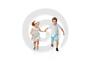 Happy children, little caucasian boy and girl jumping and running isolated on white background