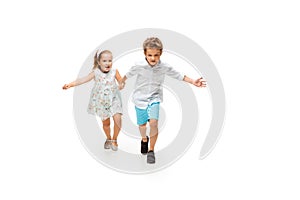 Happy children, little caucasian boy and girl jumping and running isolated on white background