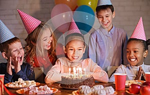 Happy children looking at birthday cake with candles
