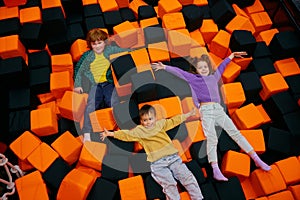 Happy children lying in dry pool with soft cube in entertainment center