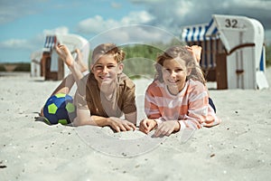 Happy children lying on white sand at sea at sunny day