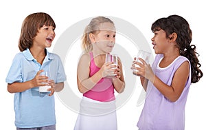 Happy, children and milk in glasses with nutrition, health and wellness in white background of studio. Calcium, drink