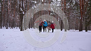 Happy children and mom and dad run with the children in the winter forest. parents play with children in a snowy park in