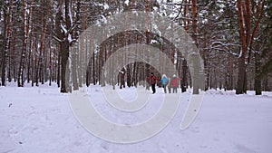 Happy children and mom and dad run with the children in the winter forest. parents play with children in a snowy park in