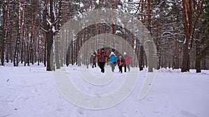 Happy children and mom and dad run with the children in the winter forest. parents play with children in a snowy park in