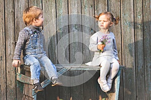 Happy children outdoor at fall season, sitting at bench. First date