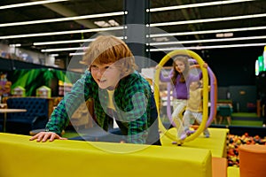 Happy children passing road of obstacles on indoor playground