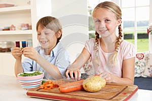 Happy children peeling vegetables in kitchen