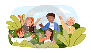Happy children peeping, hiding behind plants in park. Cute kids group greeting, waving with hand, portrait. Boys, girls