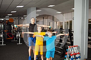 Happy children perform physical exercises in gym with a coach