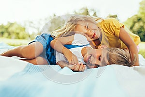 Happy children playing on the blanket outdoors. Cheerful little boy and cute little girl smiling and relaxing in the park. Kids