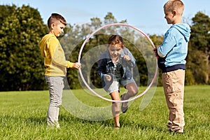 happy children playing game with hula hoop at park