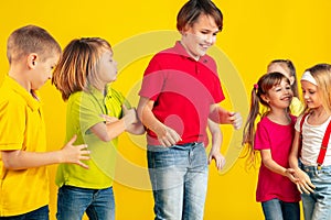 Happy children playing and having fun together on yellow studio background