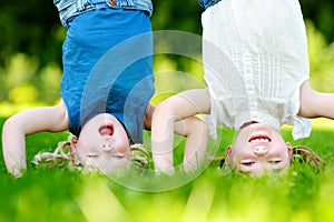 Happy children playing head over heels on green grass