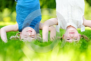 Happy children playing head over heels on green grass