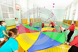 Happy children playing parachute game in gym