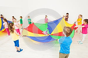 Happy children playing parachute games in gym