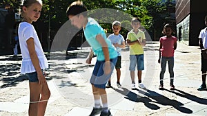 Happy children playing rubber band jumping game and laughing outdoors