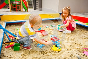 Happy children playing with sand at modern playground outside