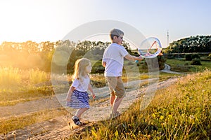 Happy children playing with soap bubbles on a summer nature. Bubbles in the sunset