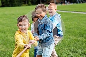 happy children playing tug-of-war game at park