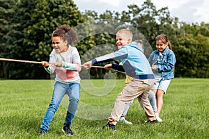 happy children playing tug-of-war game at park