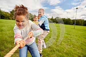 happy children playing tug-of-war game at park