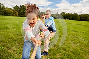happy children playing tug-of-war game at park