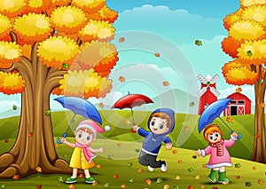 Happy children playing with umbrellas in farm landscape