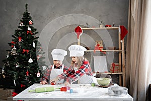 Happy children preparing cookies or gingerbread for christmas, decorated background, brother and sister cut out cookies
