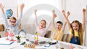 Happy children with raised hands after robotics class