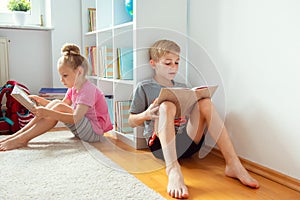 Happy children reading books on the floor at the school library