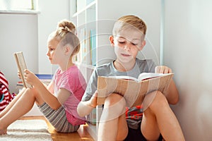 Happy children reading books on the floor at the school library