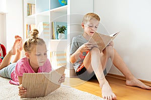 Happy children reading books on the floor at the school library