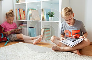 Happy children reading books on the floor at the school library