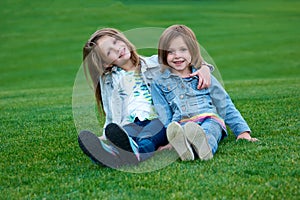 Happy children relaxing on green grass in summer park.