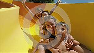 Happy children are riding down a slide in aquapark